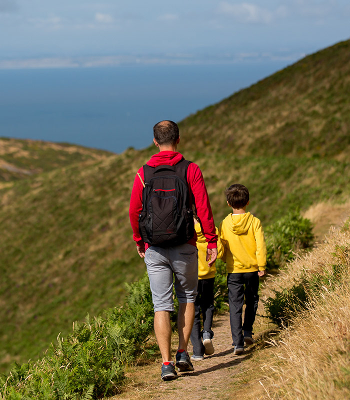 From behind, a man and his son walking along the hills 