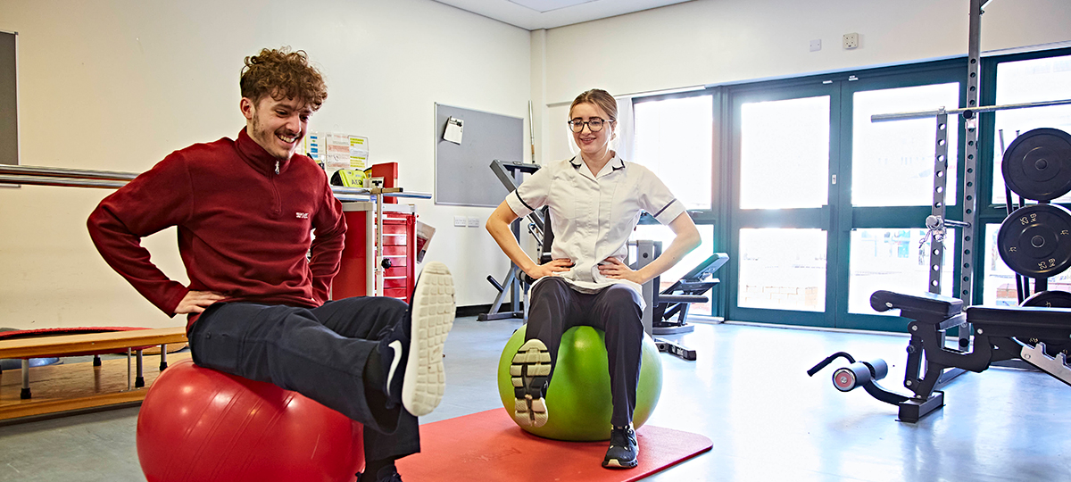 A physiotherapist and a patient performing exercises on exercise balls 