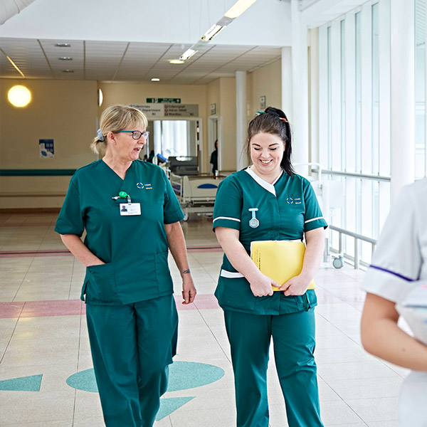 Two women colleagues walking together down hospital corridoor 