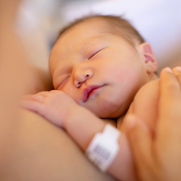 Newborn baby sleeping on someones blurred out chest