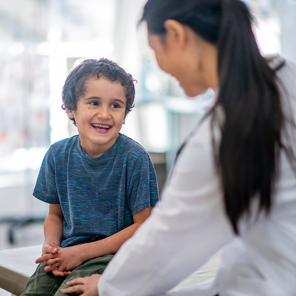 Young boy smiling at health professional with back to frame