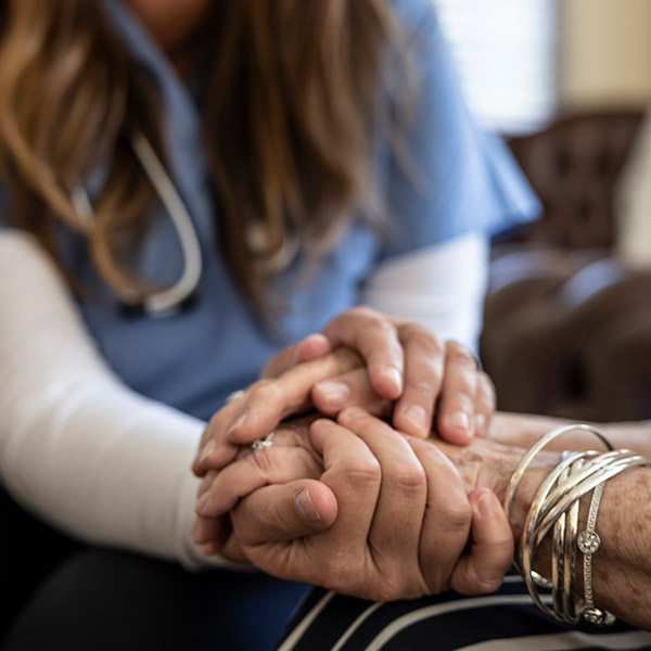 Patient and clinical professional holding hands, with just hands in frame 