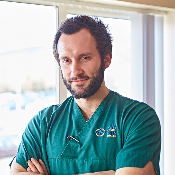 Male medical professional with arms crossed smiling away from camera 