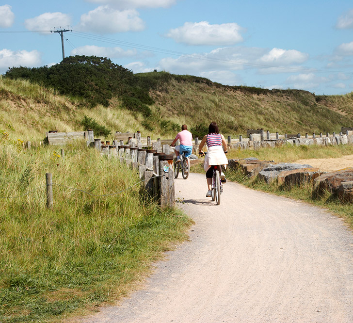 Family Cycling Along Coastal Path On Bikes 